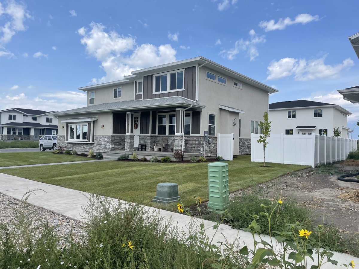 Completed gray and white home with stonework and a landscaped yard