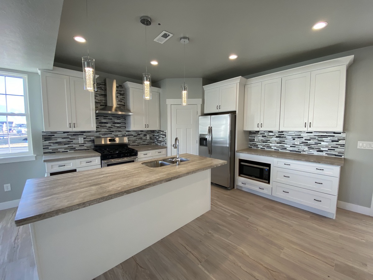 White kitchen with a wood counter island and dark backsplash