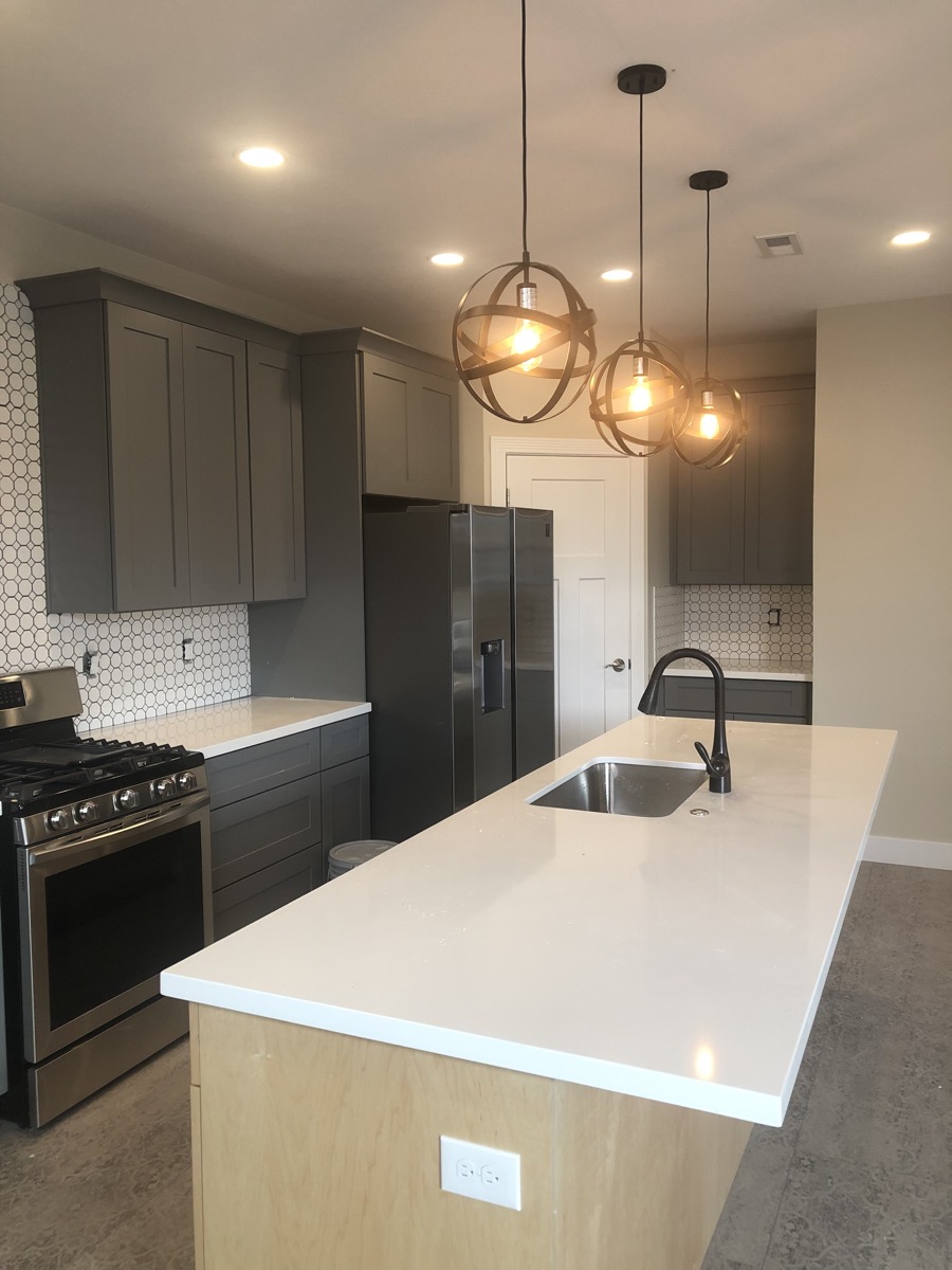 Charcoal kitchen with white counters and globe pendant lights